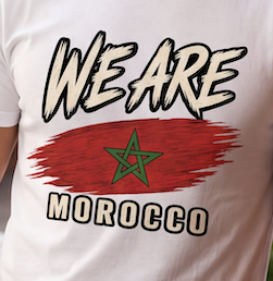 A close-up of a white t-shirt featuring a graphic print with the text 'WE ARE MOROCCO' and a red brushstroke design containing the green Moroccan star.