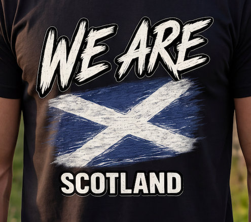A close-up of a black t-shirt featuring a distressed graphic of the Scottish flag with the text 'WE ARE SCOTLAND' in white with black outlines.