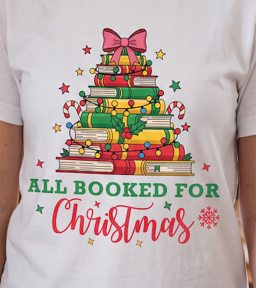Close-up of white All Booked for Christmas shirt showing the festive stacked book Christmas tree design.