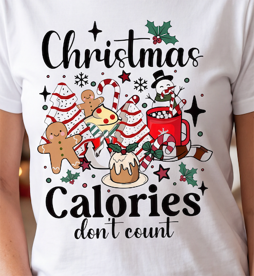 Close-up of white Christmas Calories Don’t Count shirt with gingerbread, candy canes, cocoa and festive treats.