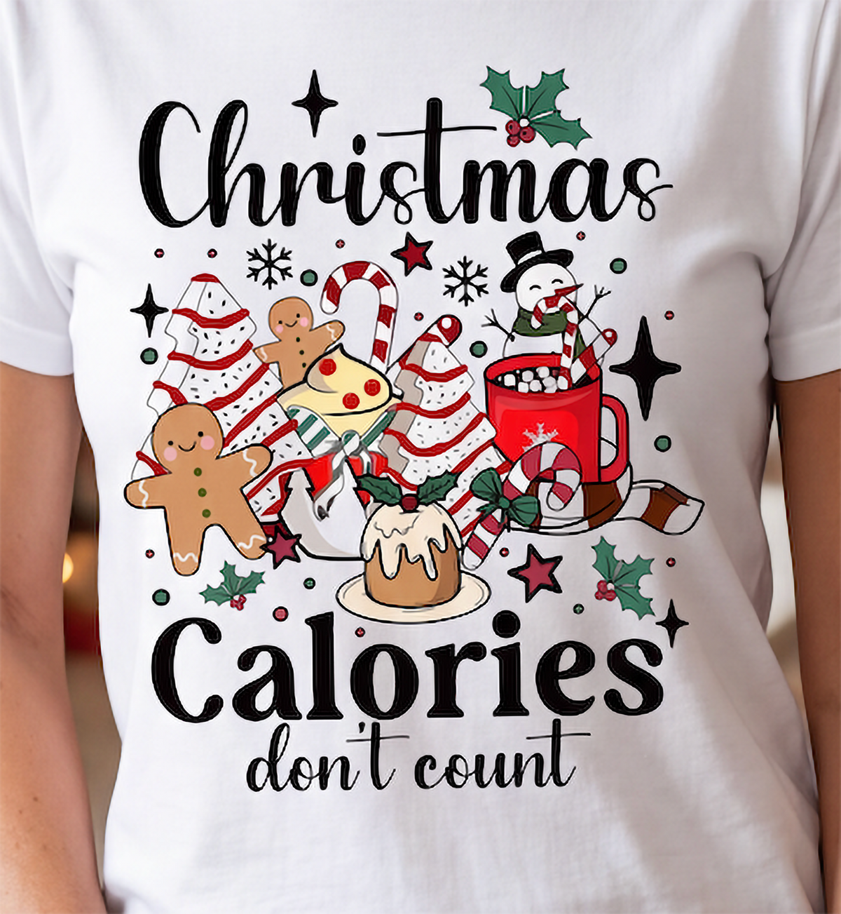 Close-up of white Christmas Calories Don’t Count shirt with gingerbread, candy canes, cocoa and festive treats.