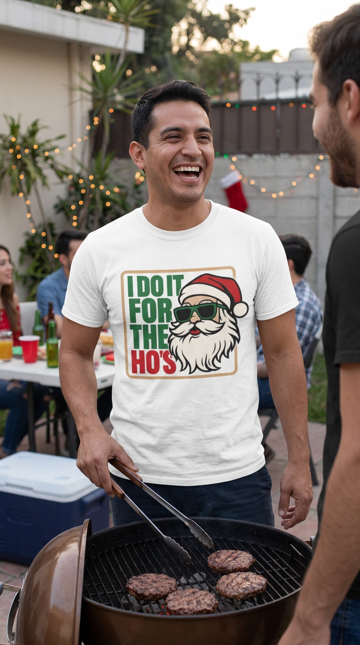 Man wearing a white funny Santa Christmas graphic tee at an outdoor holiday gathering.