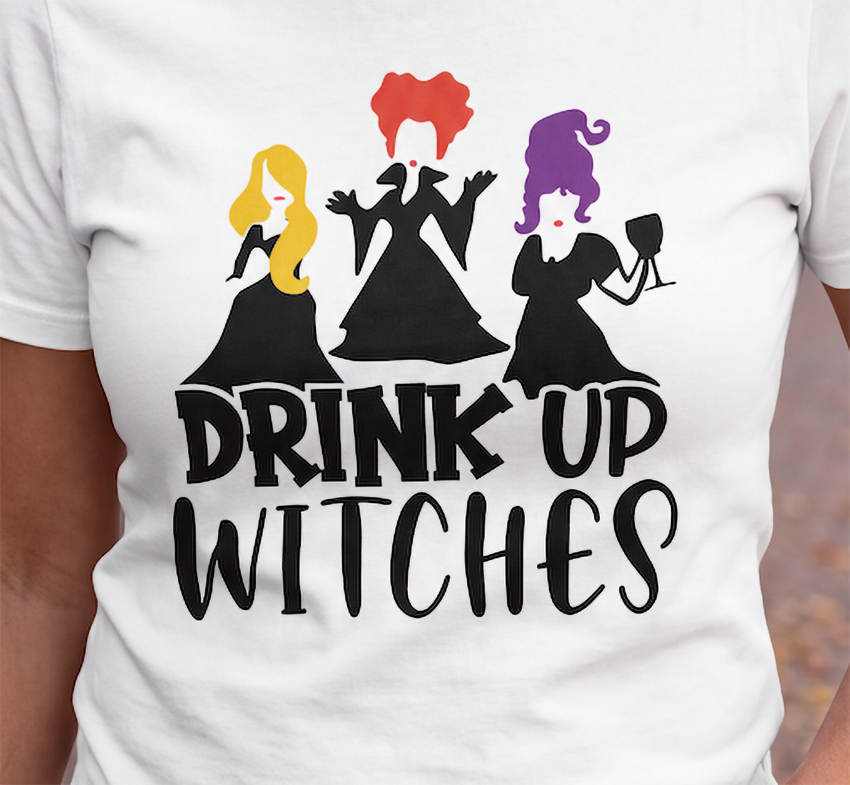 Close-up of white Drink Up Witches Halloween shirt with colorful witch design