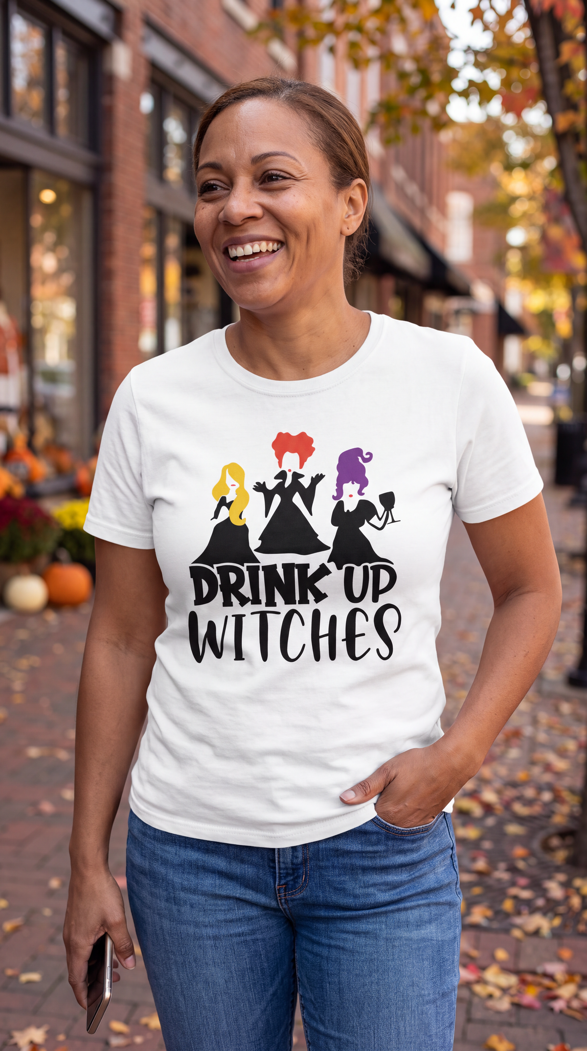 Woman wearing white Drink Up Witches Hocus Pocus Halloween shirt outdoors