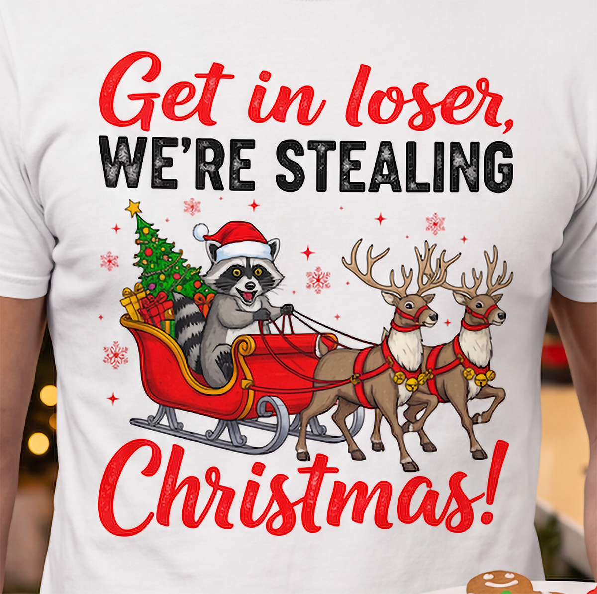 Close-up of Get in Loser We’re Stealing Christmas raccoon and reindeer design on a white T-shirt