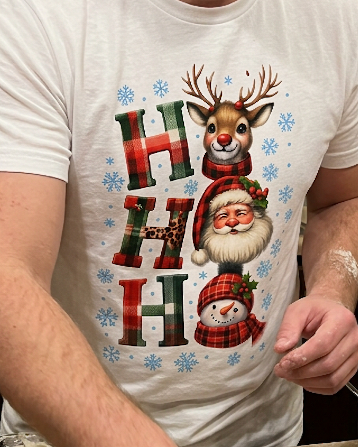 Close-up of white Ho Ho Ho Christmas shirt featuring adorable holiday characters, plaid letters and winter snowflakes.