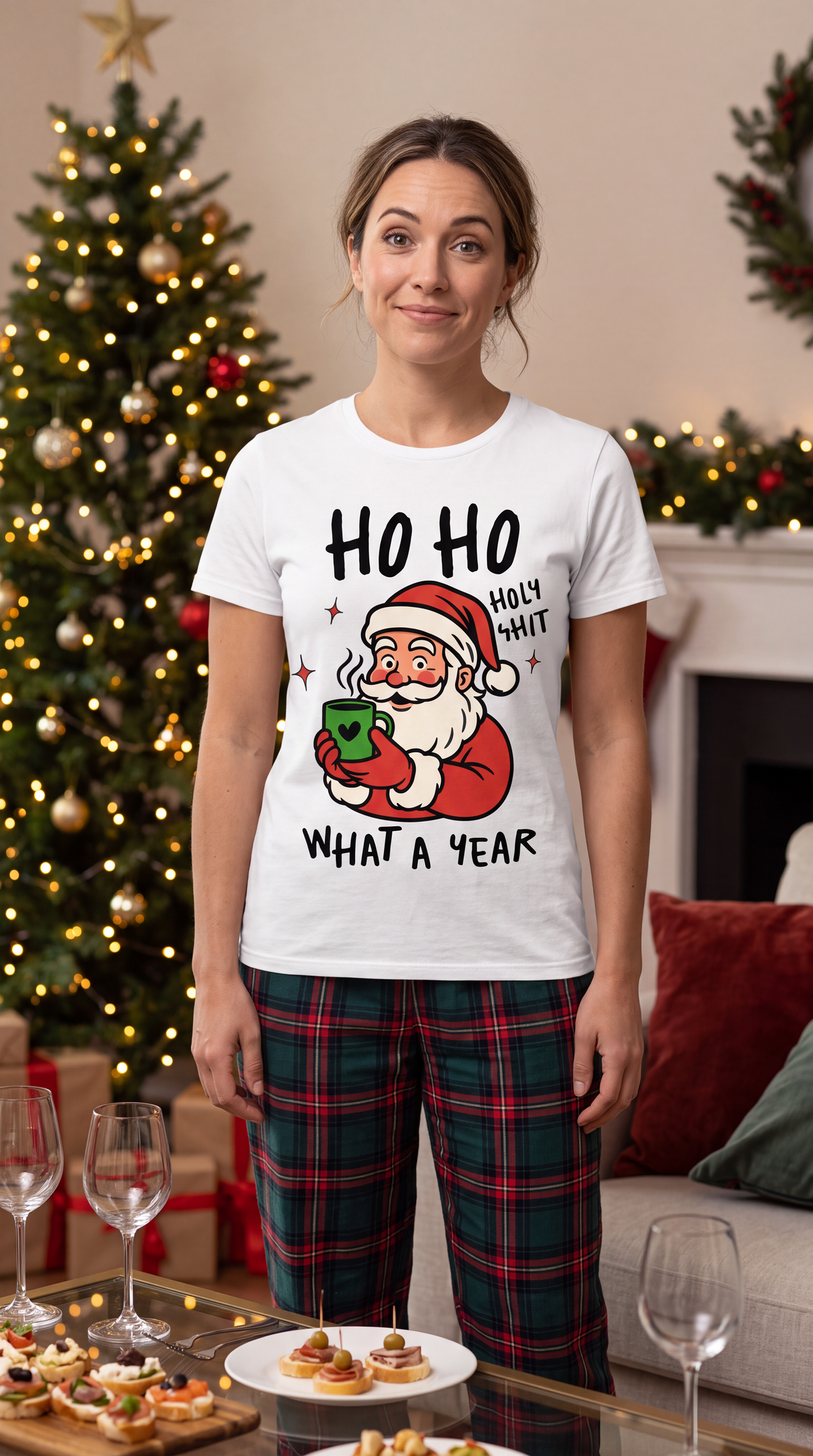 Woman wearing white Ho Ho Holy Shit Christmas shirt featuring funny Santa holding a green mug in a festive holiday setting.