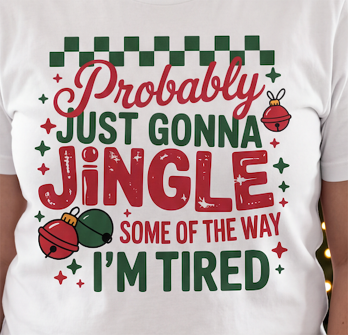 Close-up of Probably Just Gonna Jingle Some of the Way I’m Tired Christmas graphic with jingle bells and red and green lettering.