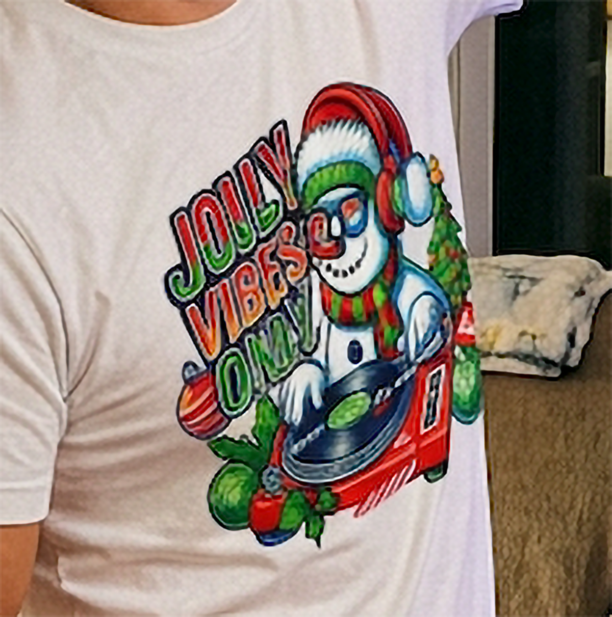 White Close-Up: Close-up of festive snowman DJ Christmas artwork printed on a sand-colored holiday graphic tee.