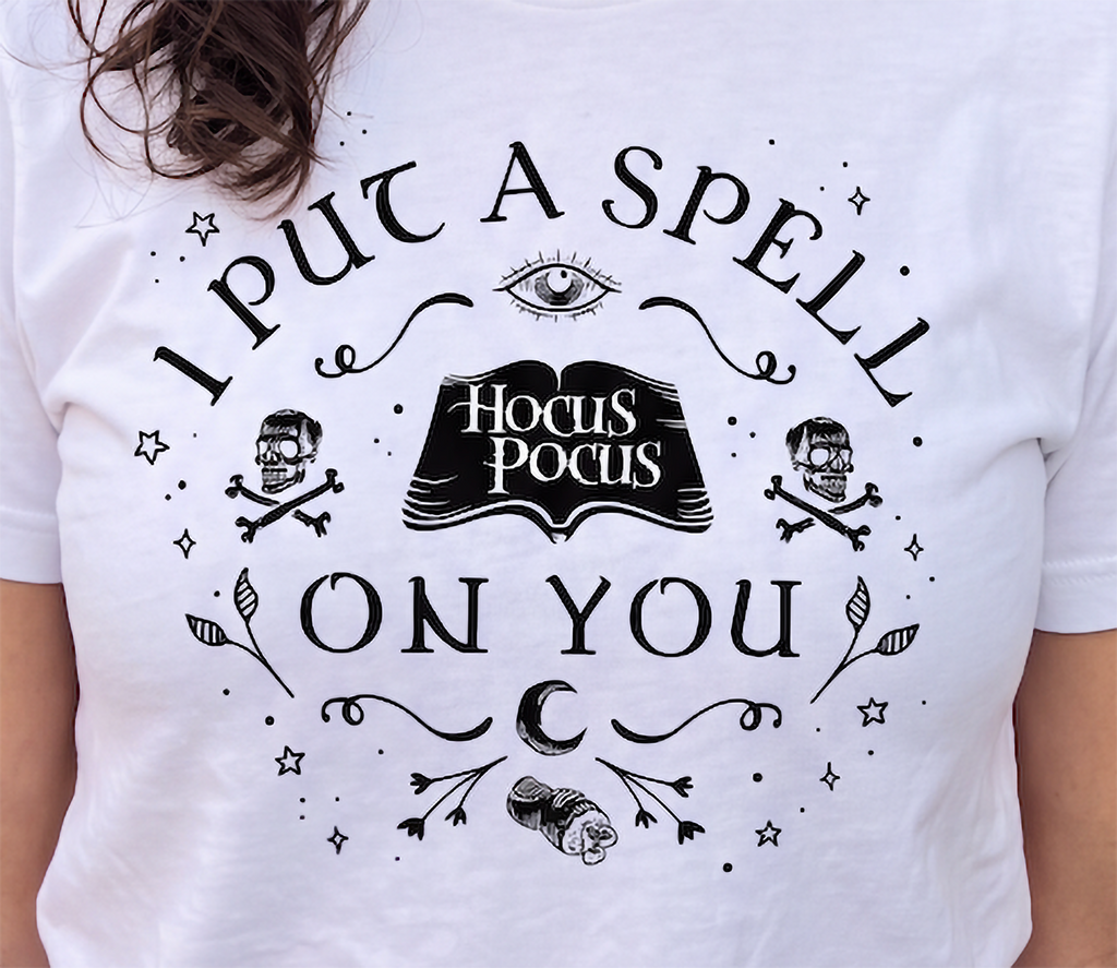 Close-up of white Hocus Pocus witchy Halloween shirt with spellbook design