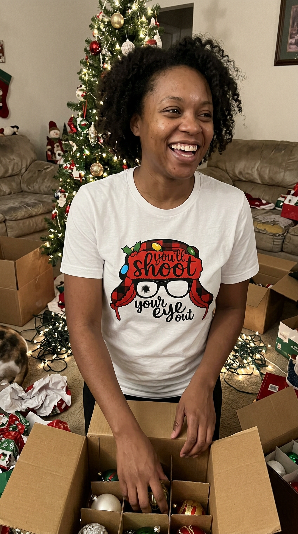 Woman wearing white You'll Shoot Your Eye Out Christmas graphic tee at a festive indoor holiday gathering