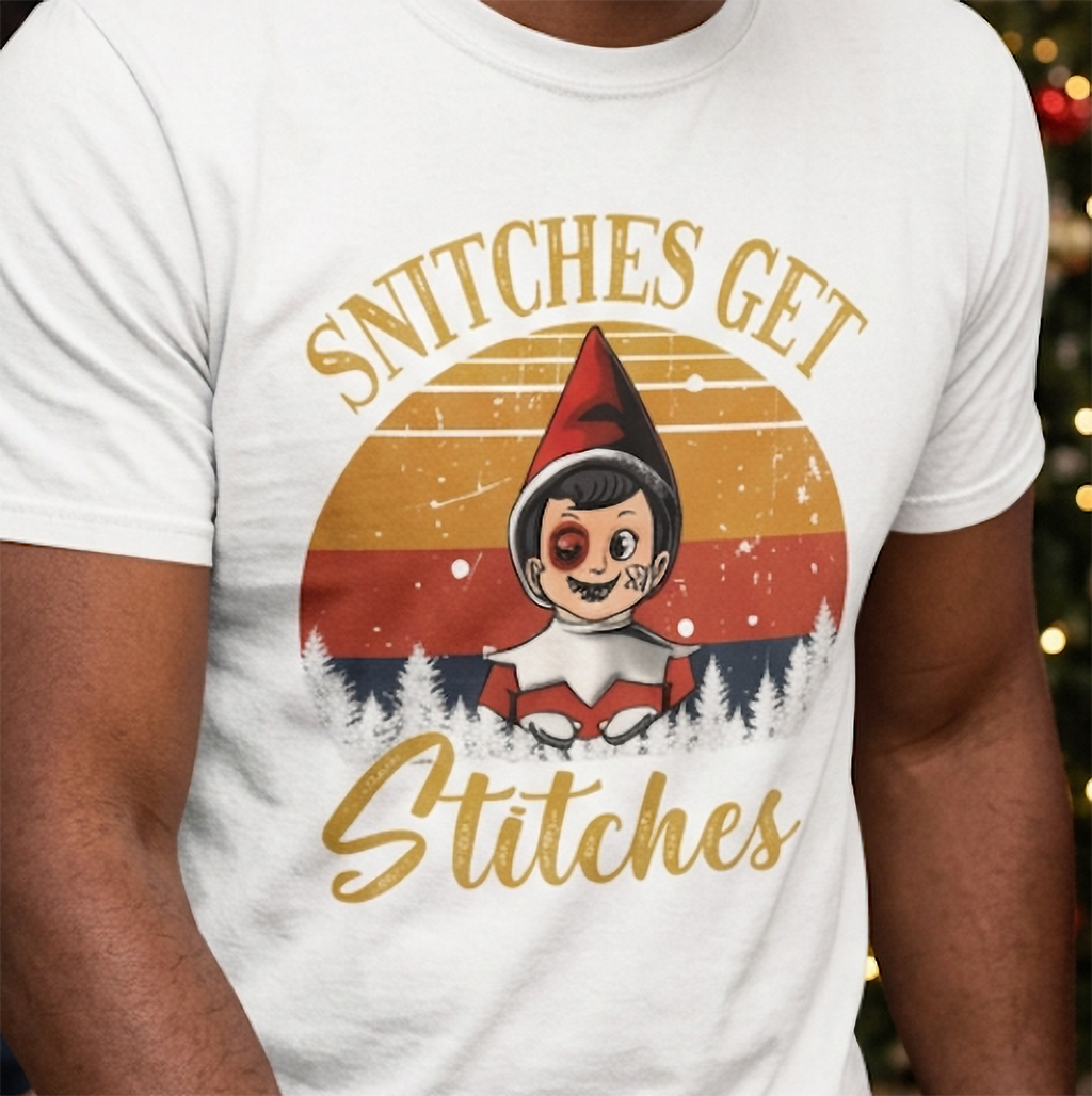 Close-up of retro Christmas elf design with Snitches Get Stitches saying printed on a white graphic t-shirt.