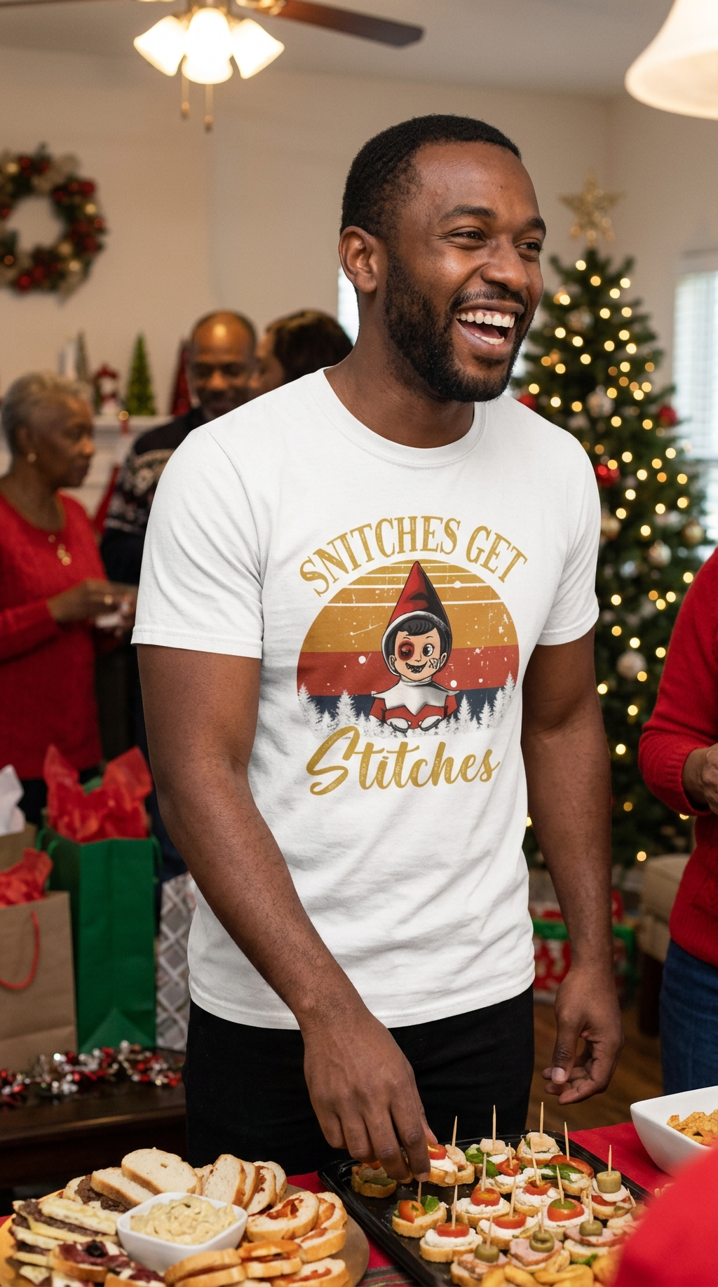 Smiling man wearing a white Snitches Get Stitches funny Christmas elf shirt at a festive holiday party.