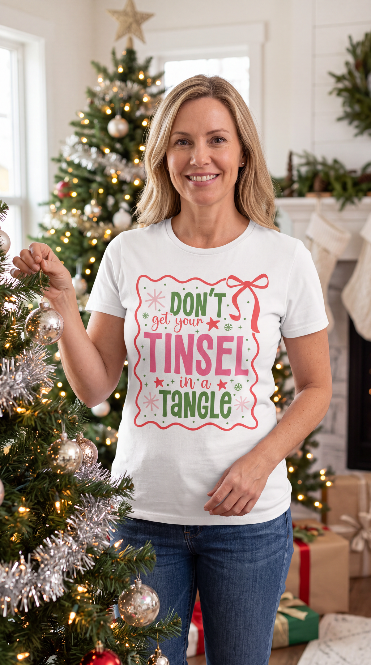 Woman wearing a white Don’t Get Your Tinsel in a Tangle Christmas graphic tee in a festive holiday setting.