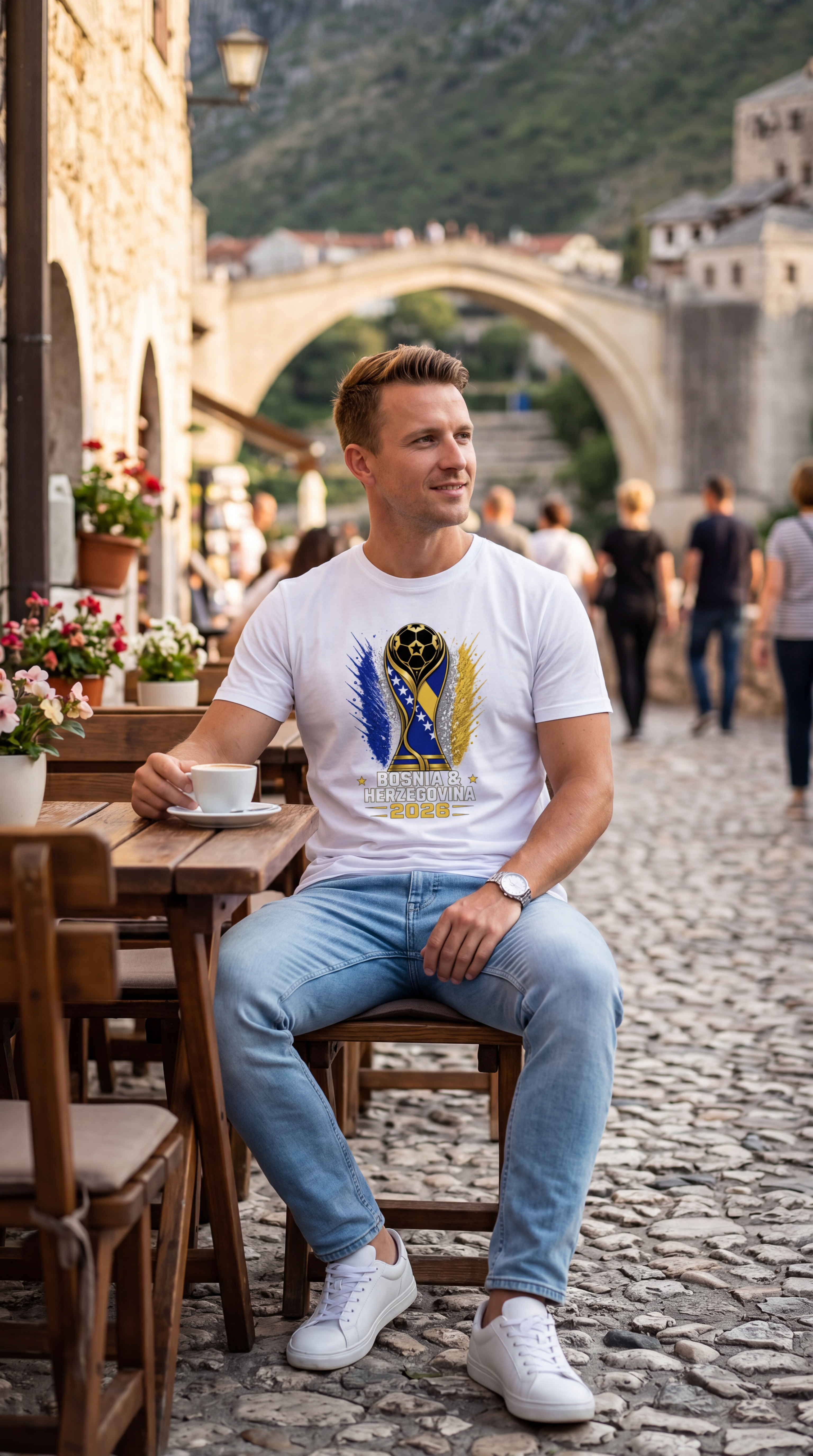 Man sitting at an outdoor cafe with a scenic bridge in the background